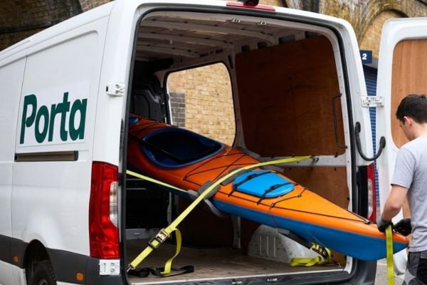 A kayak being loaded into the back of a large delivery van
